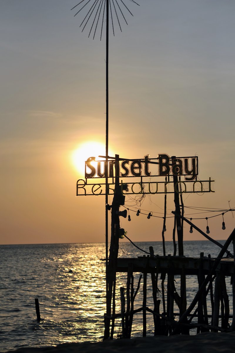 Restaurant sign silhouette against golden sunset